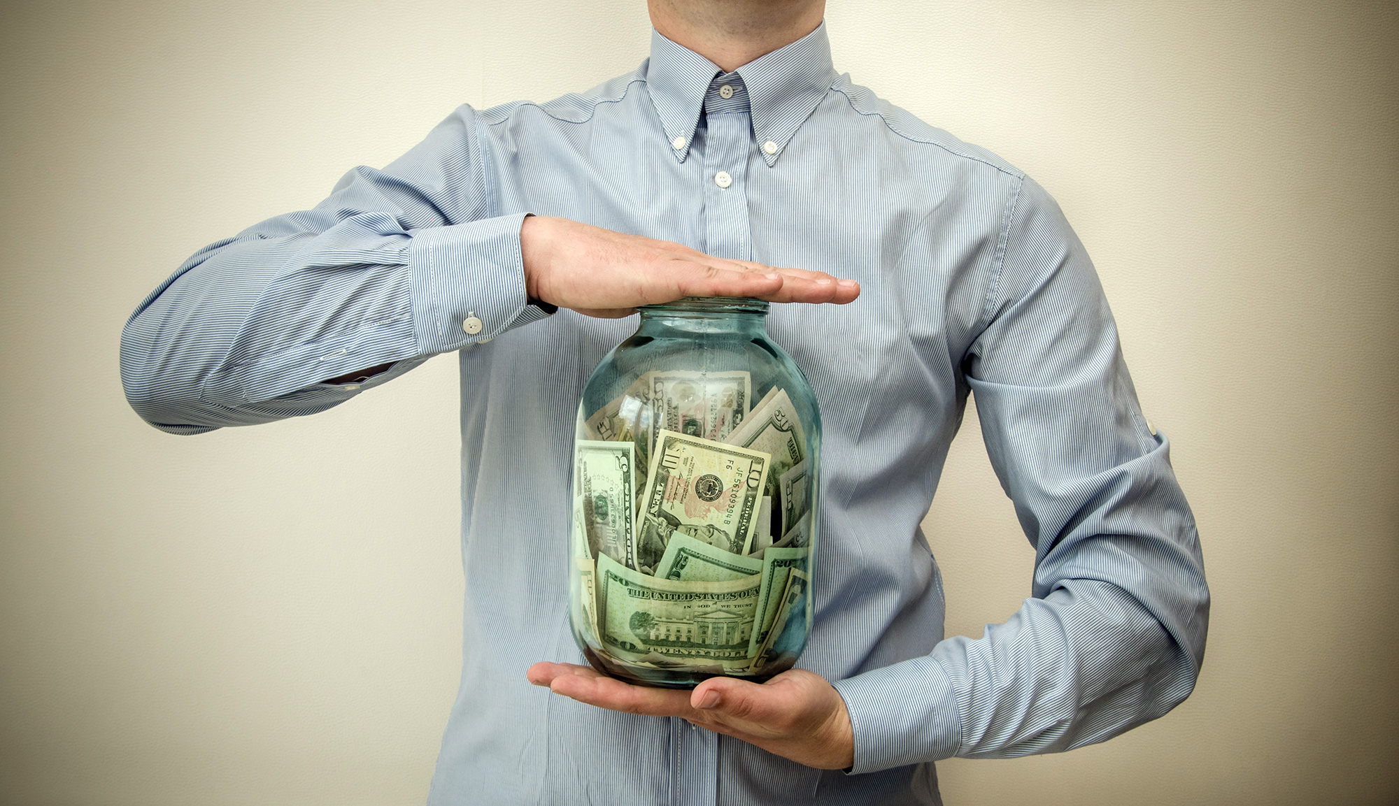 Man with tie saving money in a jar